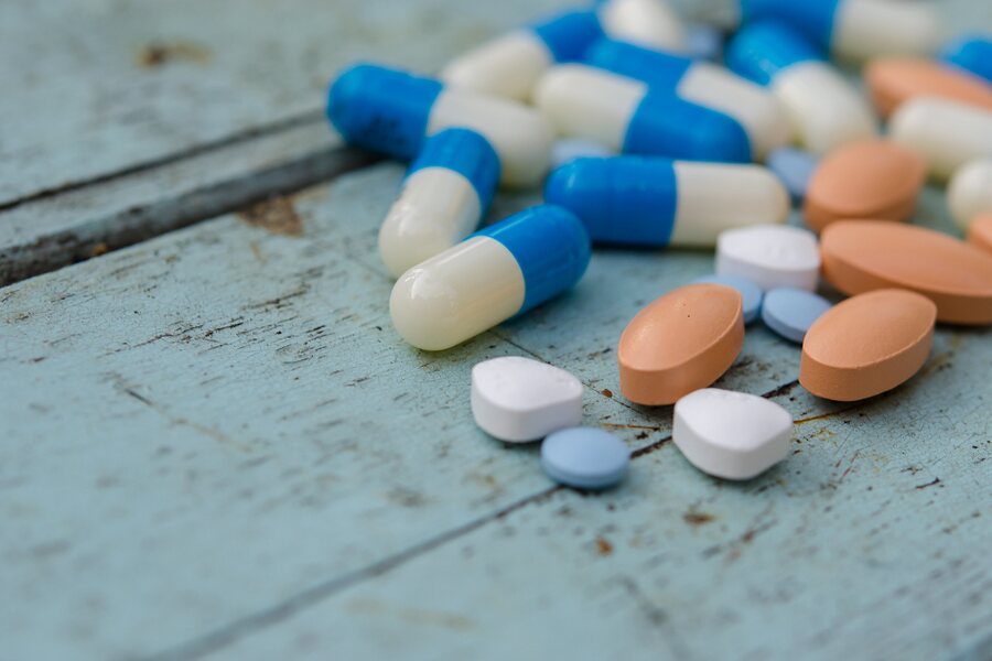 Assorted tablets and capsules on a wooden surface