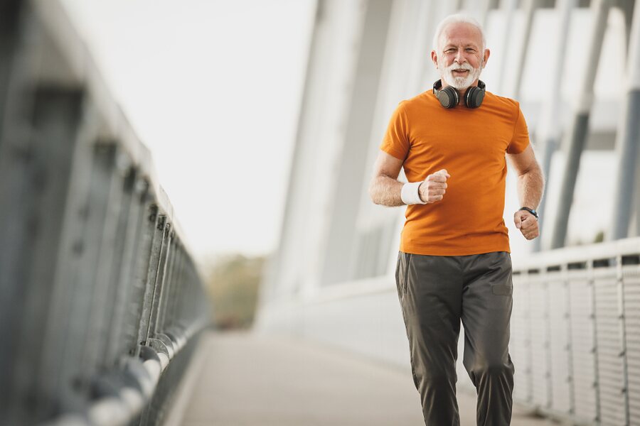 An older man walking briskly across a bridge