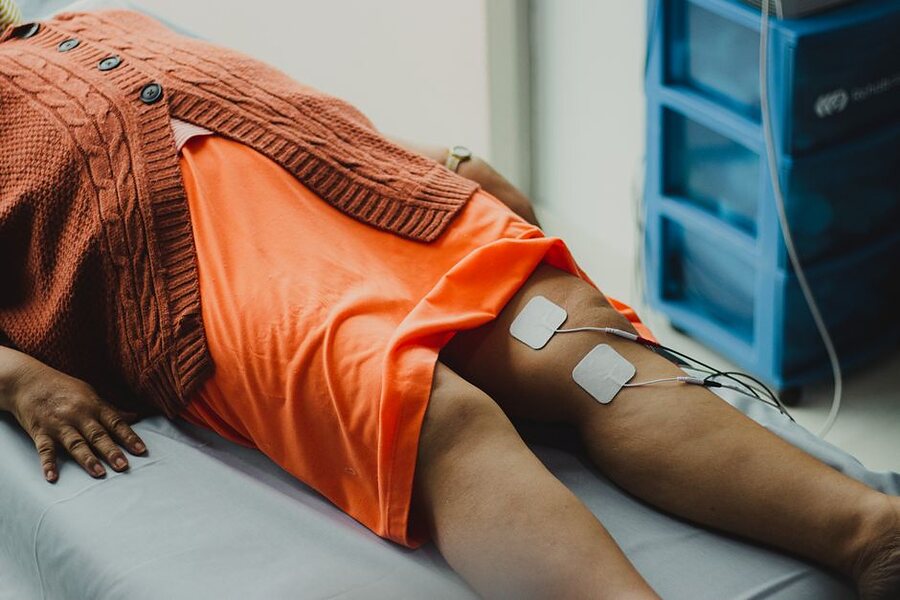 Two electrode pads on a person’s knee, wired to a therapy machine