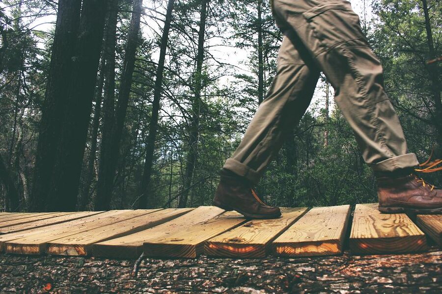 Walking boots crossing a wooden boardwalk in a forest